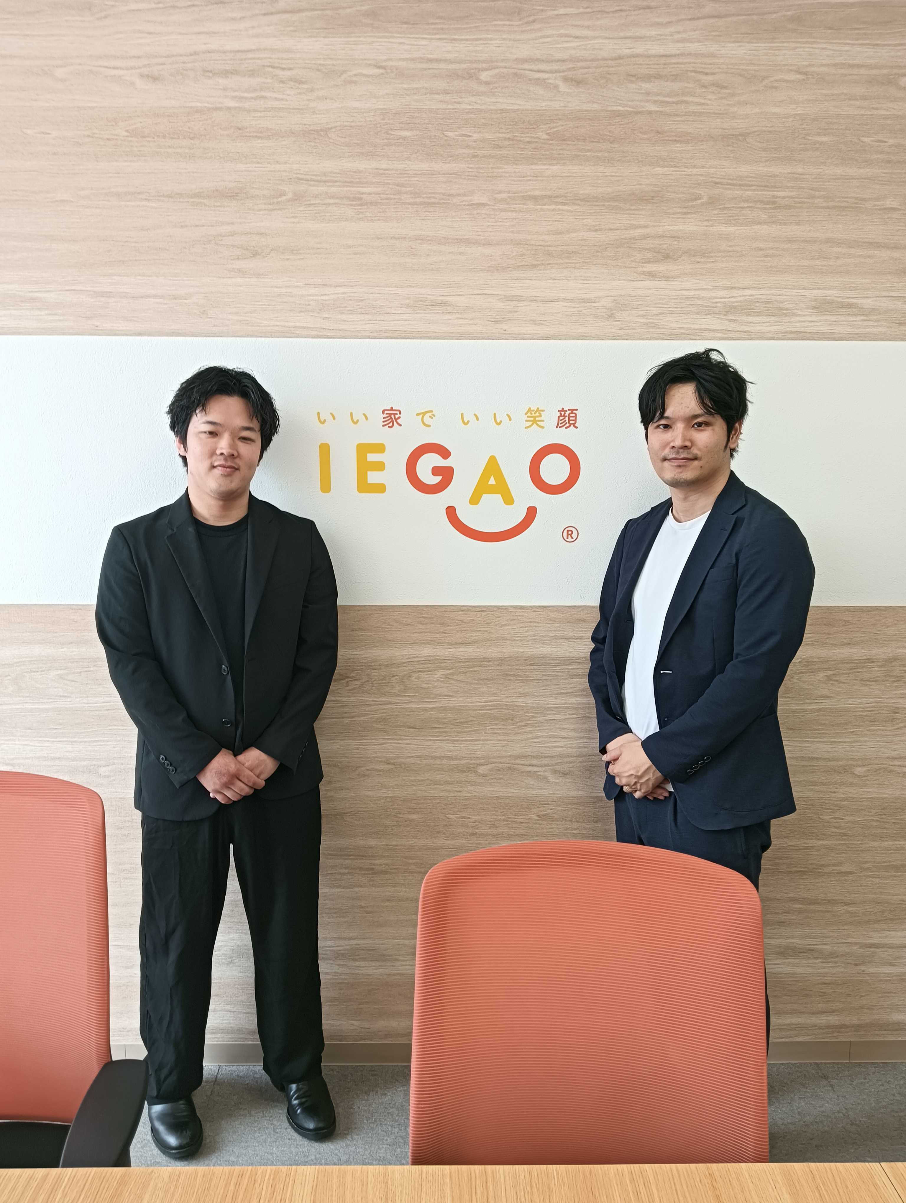 IEGAOのロゴ前に立つプロジェクト関係者